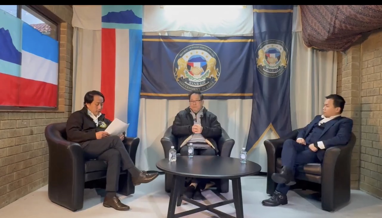 Screenshot from the community video, showing three seated speakers and Borneo flags